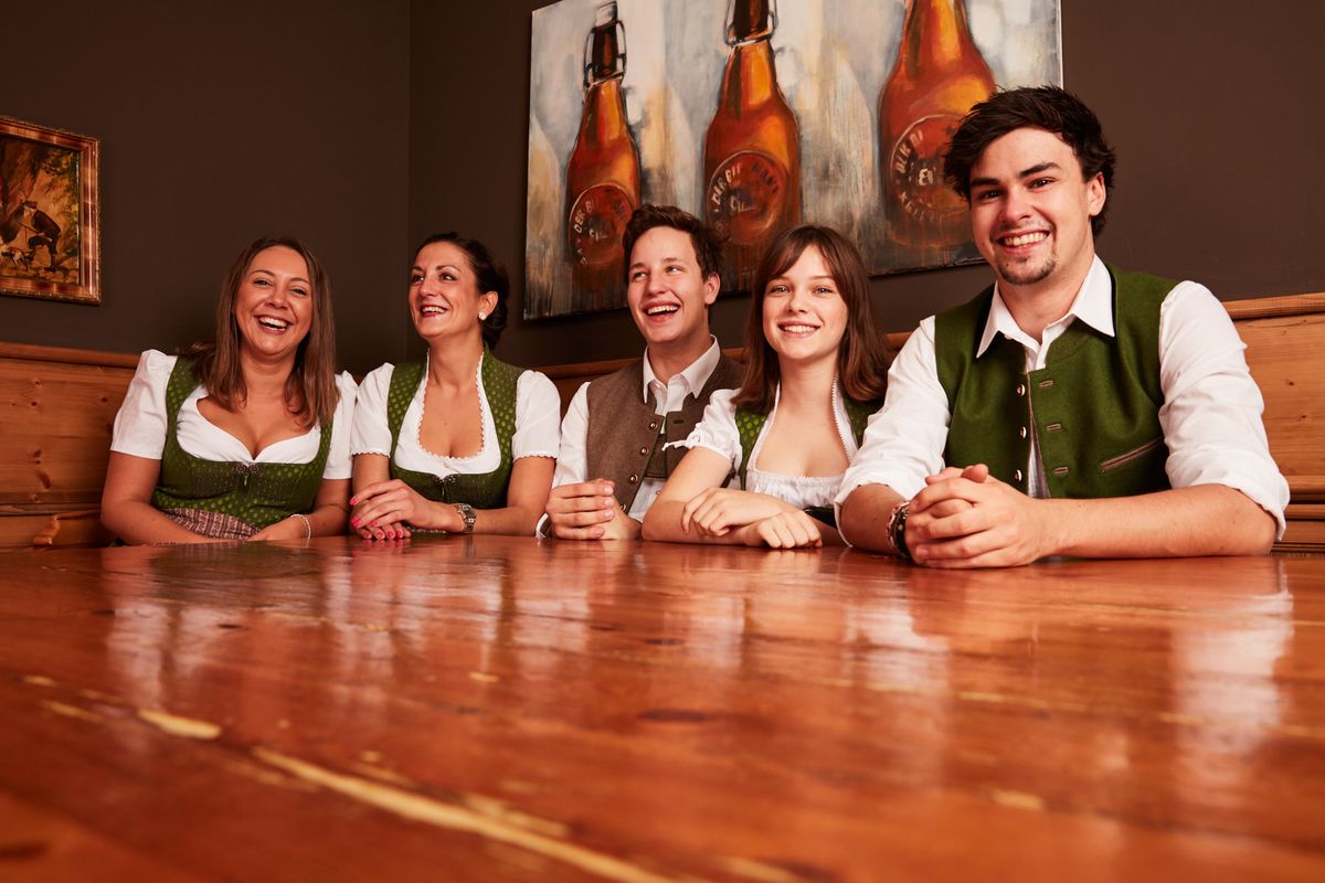 : 5 Leute in Tracht sitzen an einem Tisch Restaurant MünchenTracht Mitarbeiter